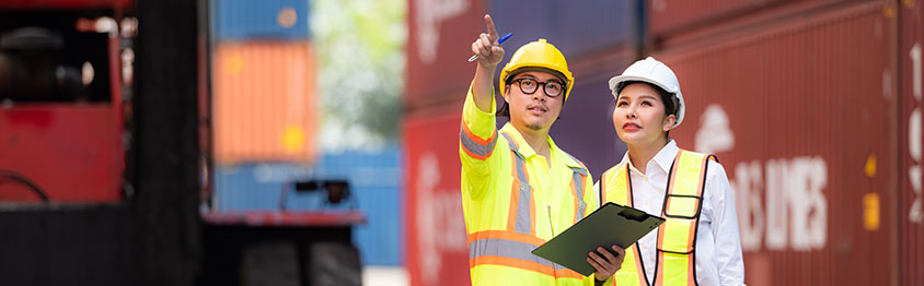 Portrait of Asian woman engineer and worker working with co-worker at overseas shipping container yard.